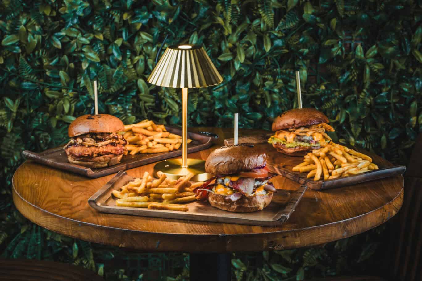 Delicious gourmet burgers with fries served on wooden trays at Gare du Nord Hostel, Paris.