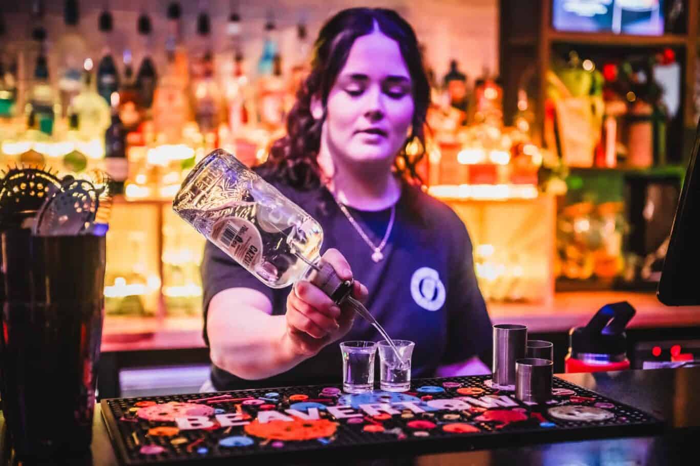 Female bartender pouring a drink at the bar in a lively pub.