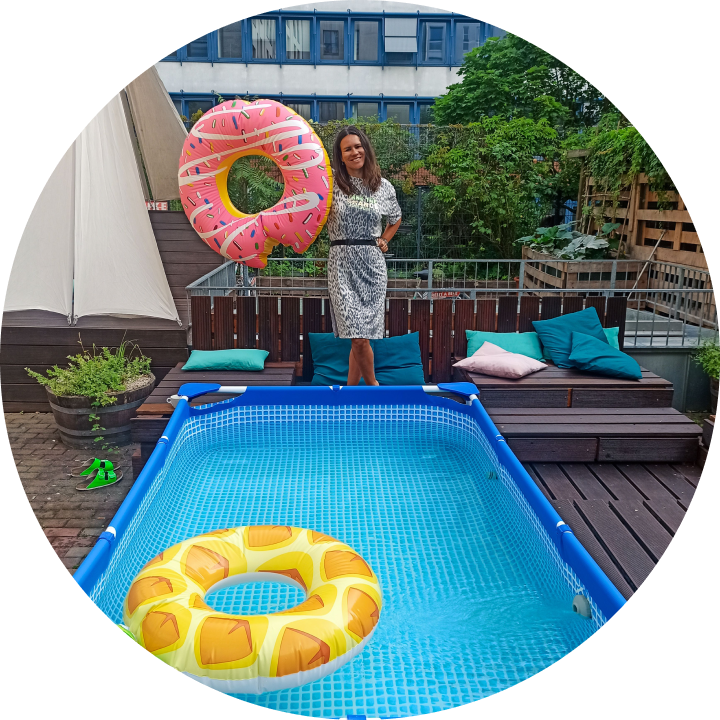 A young woman stands beside a paddling pool on a city rooftop