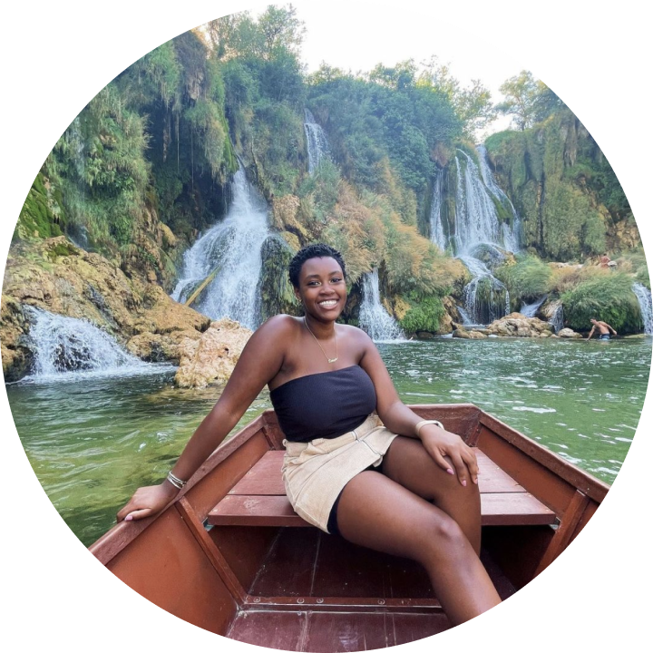 A young woman sits on a canoe in front of small waterfalls