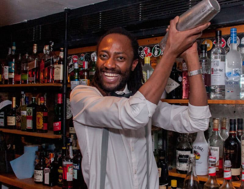 Bartender preparing a cocktail at St Christopher’s Barcelona hostel bar, with a variety of spirits i.