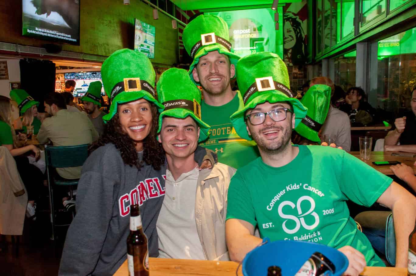 Group of friends wearing green leprechaun hats at St Christopher’s Barcelona pub during St Patrick’s.