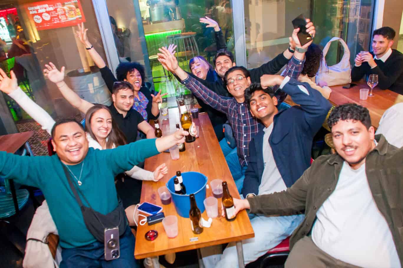Group of young people having fun and celebrating at a lively hostel bar in Barcelona.