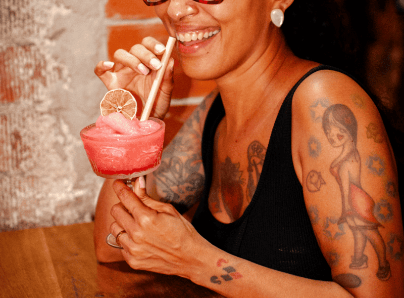 Vibrant woman enjoying a colourful cocktail at St Christopher’s Barcelona hostel.