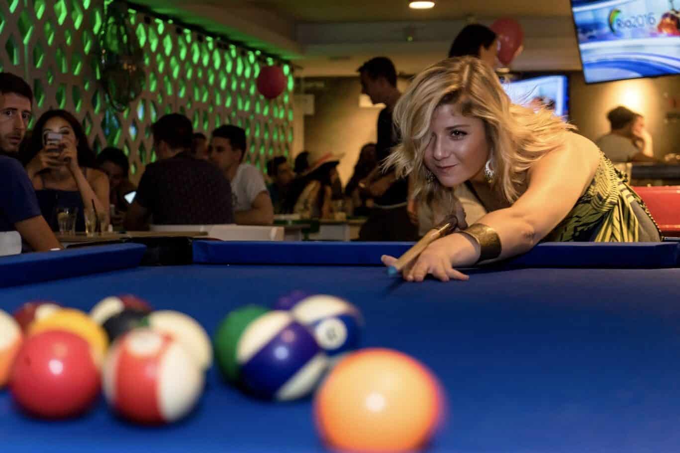 Young woman playing pool at St Christopher’s Barcelona hostel bar.
