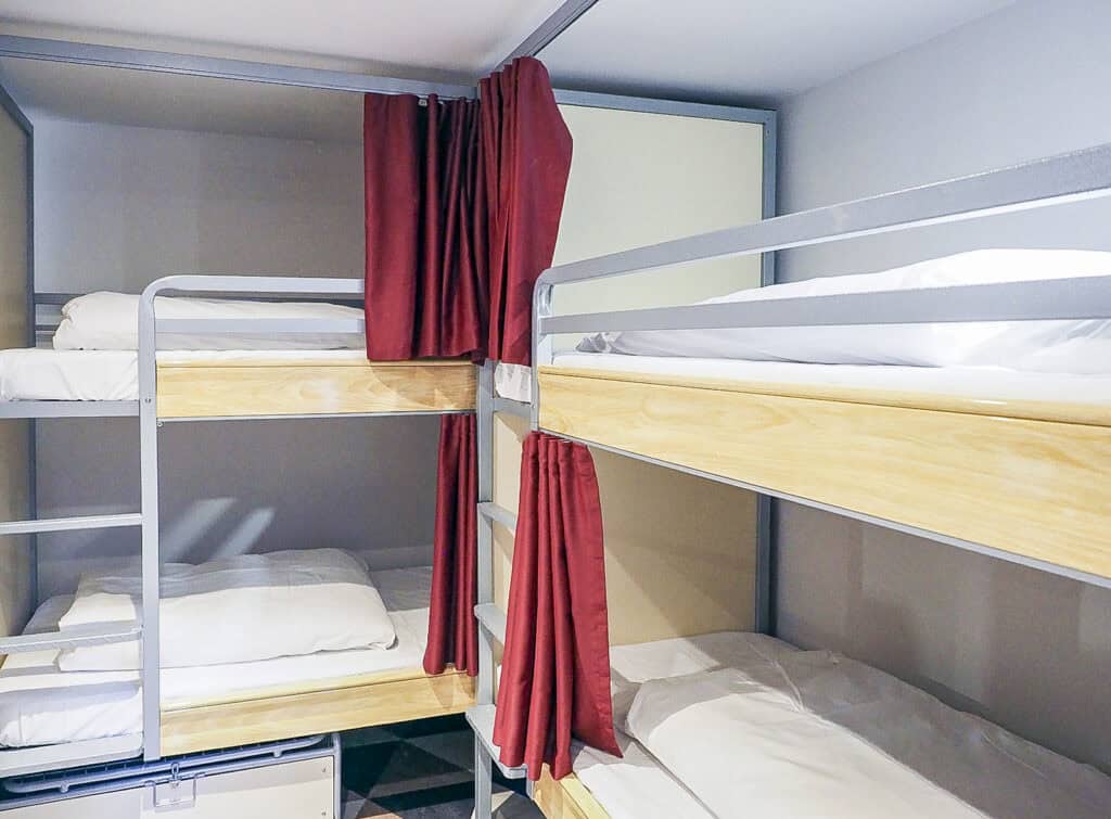 Bunk beds with red curtains in a modern hostel dormitory room.
