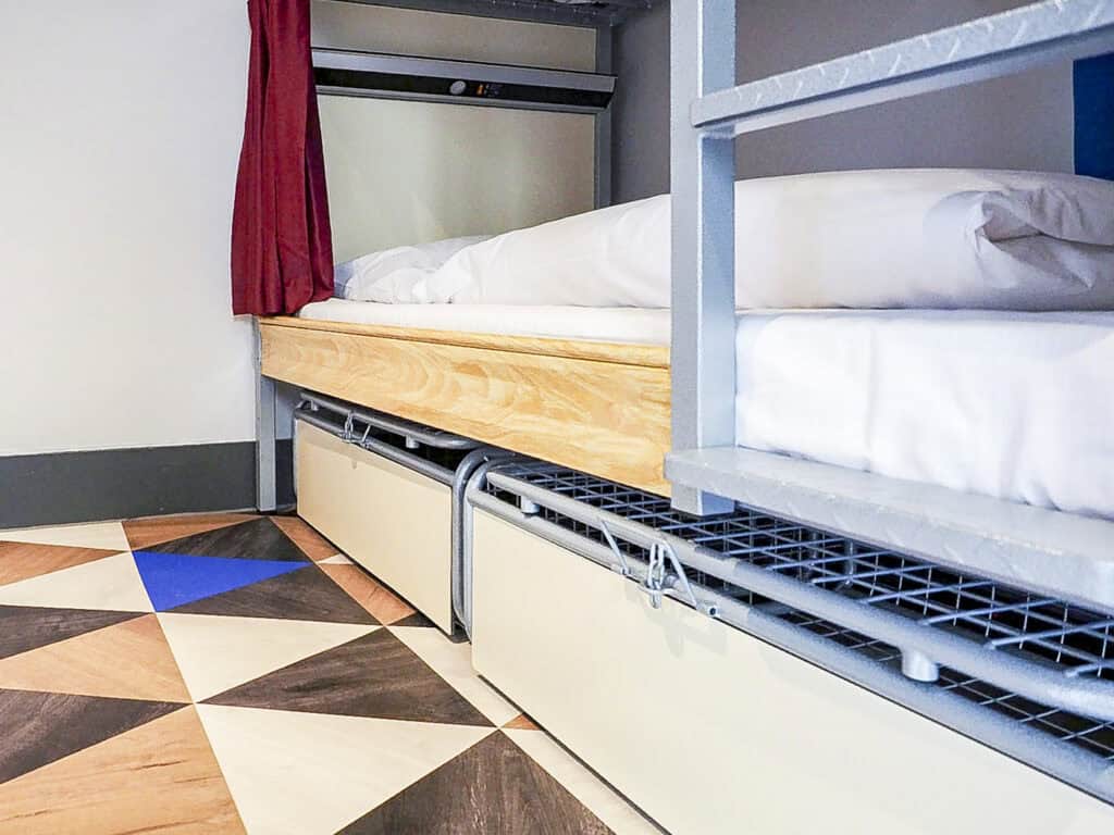 Modern bunk bed in Liverpool Street hostel room with colourful tiled floor.