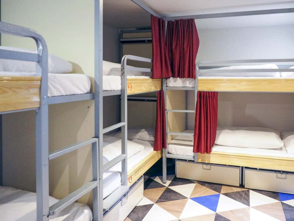 Dormitory beds with bunk beds and curtains at Liverpool Street Hostel.