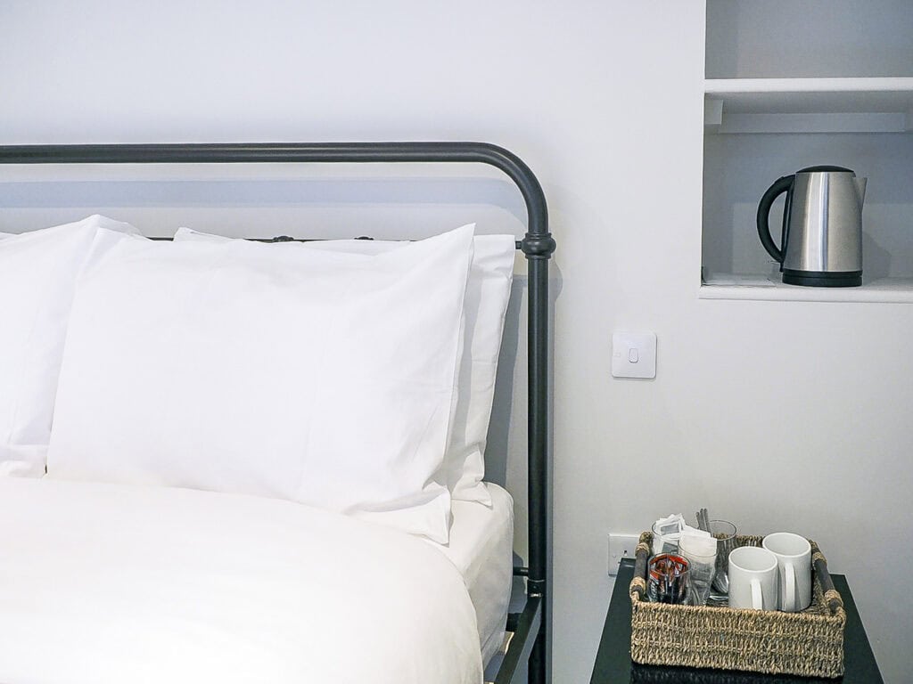 Modern hostel bedroom with white bedding and black metal bed frame.