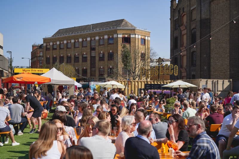 Young people having drinks in Vinegar Yard, a new street food and art market near London Bridge Station.