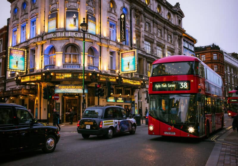 Night view of Mitte Hostel with iconic London double-decker bus in Berlin, illuminated cityscape.