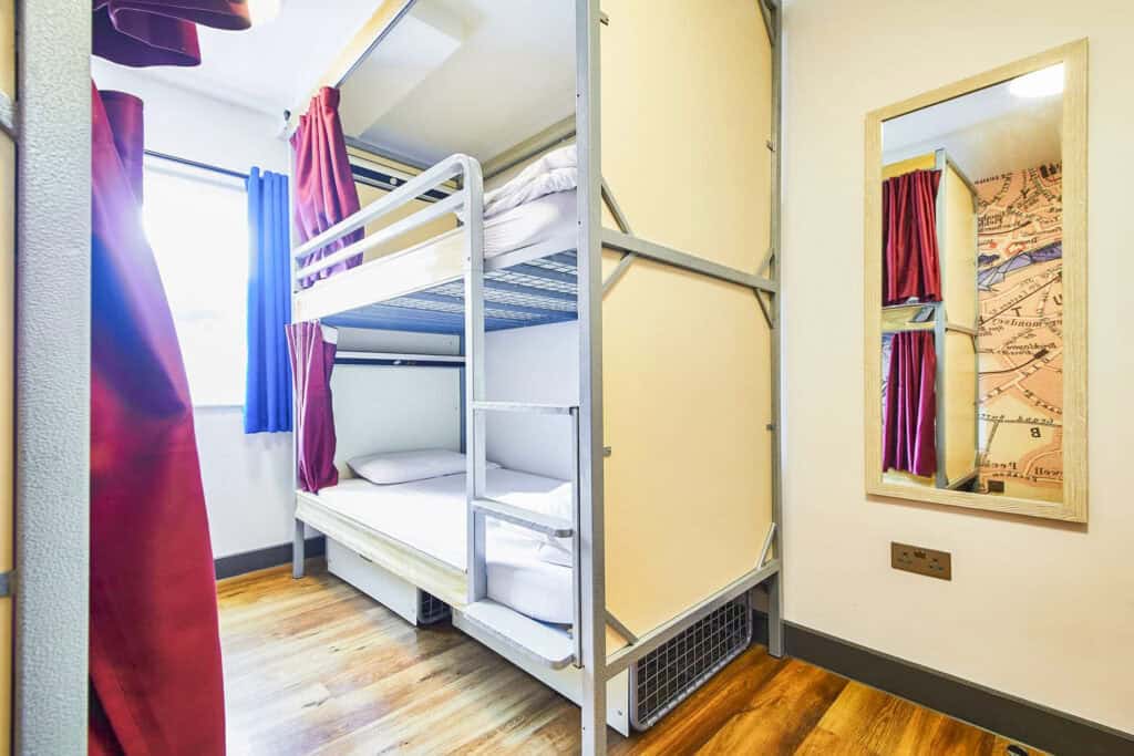 Hostel dorm room with bunk beds and colourful curtains near London Bridge.