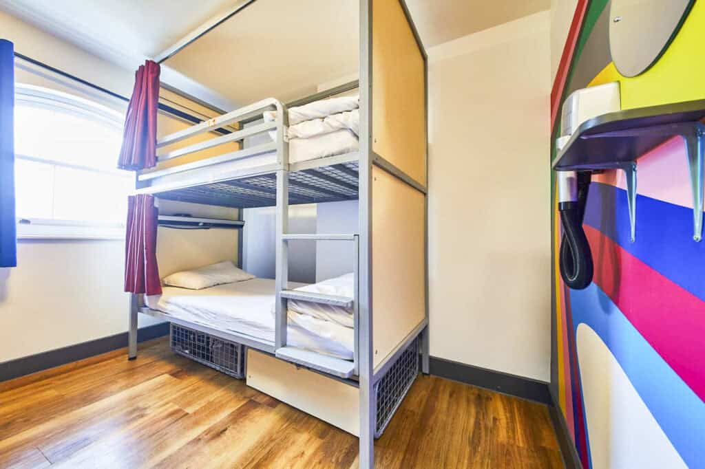 Shared dorm room at St Christopher's London Bridge with bunk beds and colourful wall art.