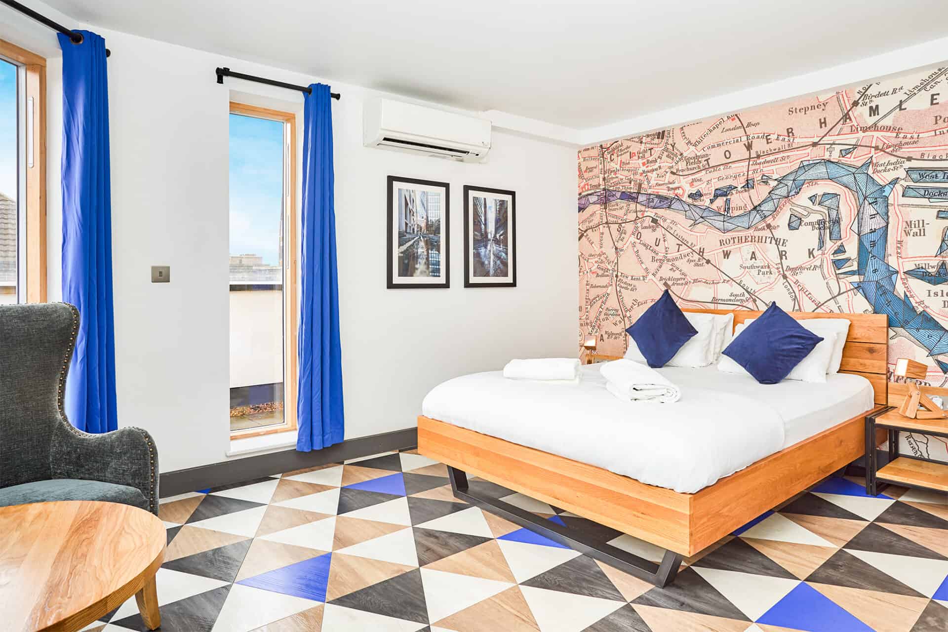 Bright hotel room with a large bed, colourful wall art, and vibrant blue curtains.