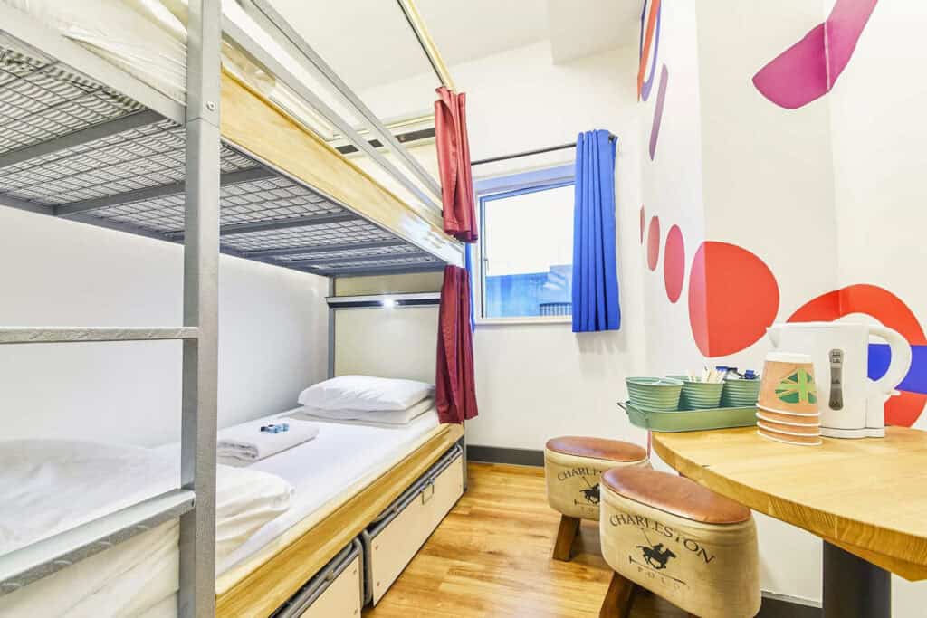 Hostel room with bunk beds, colourful decor, and a small dining area near London Bridge.