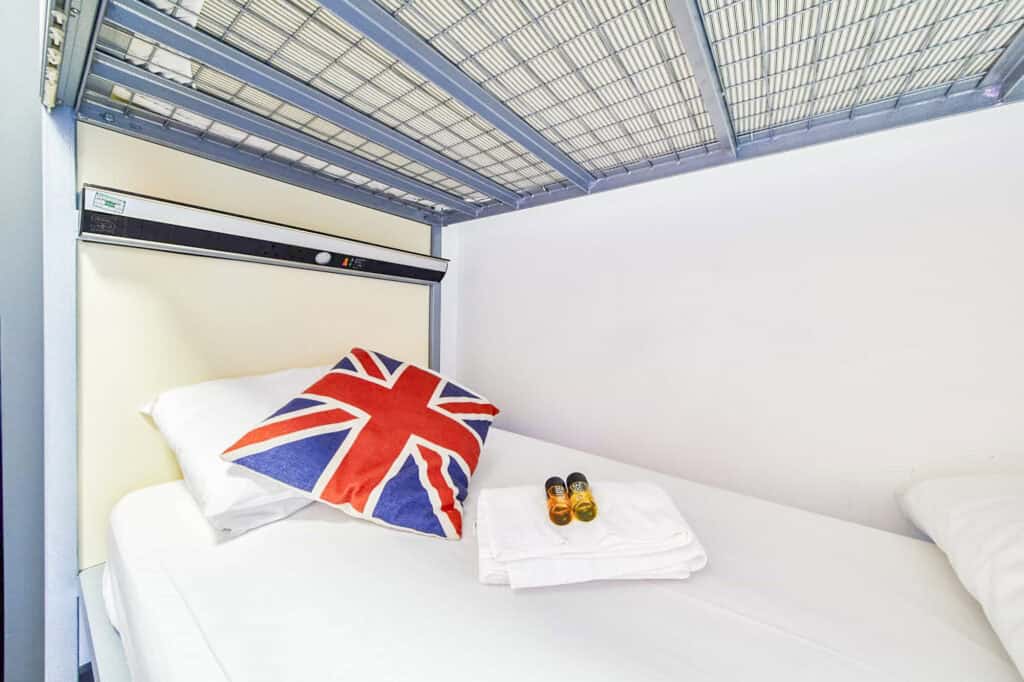 Hostel bed with Union Jack pillow under a metal bunk bed in London Bridge.