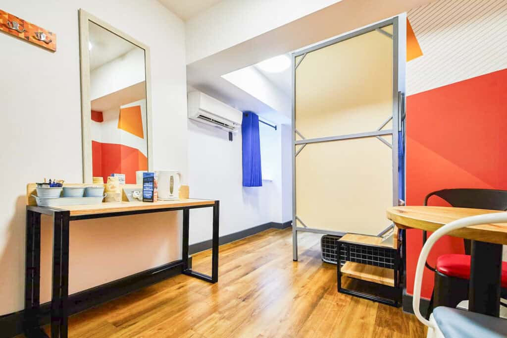 Hostel room with colourful decor, mirror, and seating area at St Christopher’s London Bridge.