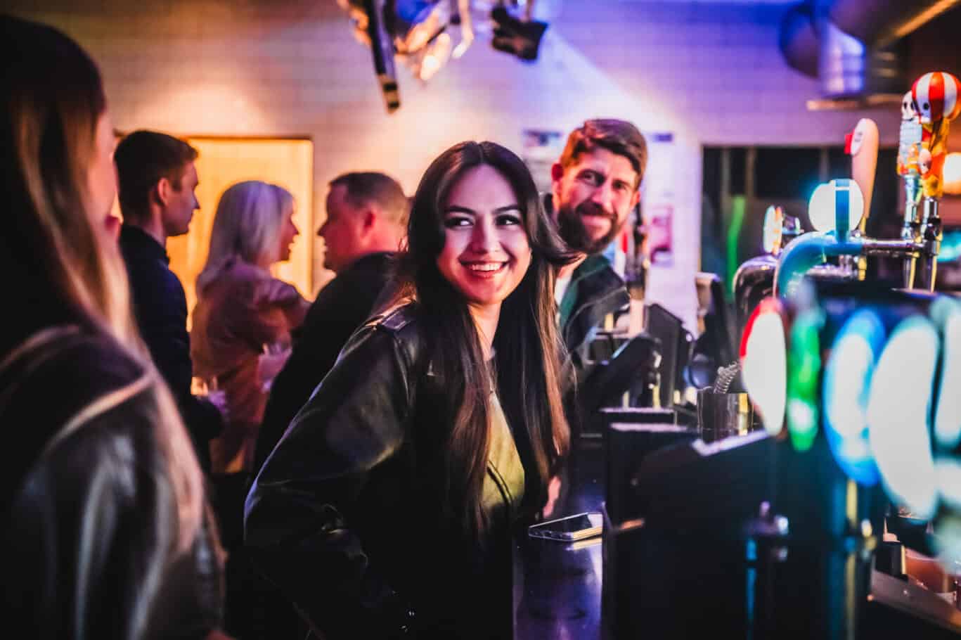 Lively bar at St Christopher’s London Bridge Hostel with happy guests enjoying drinks.