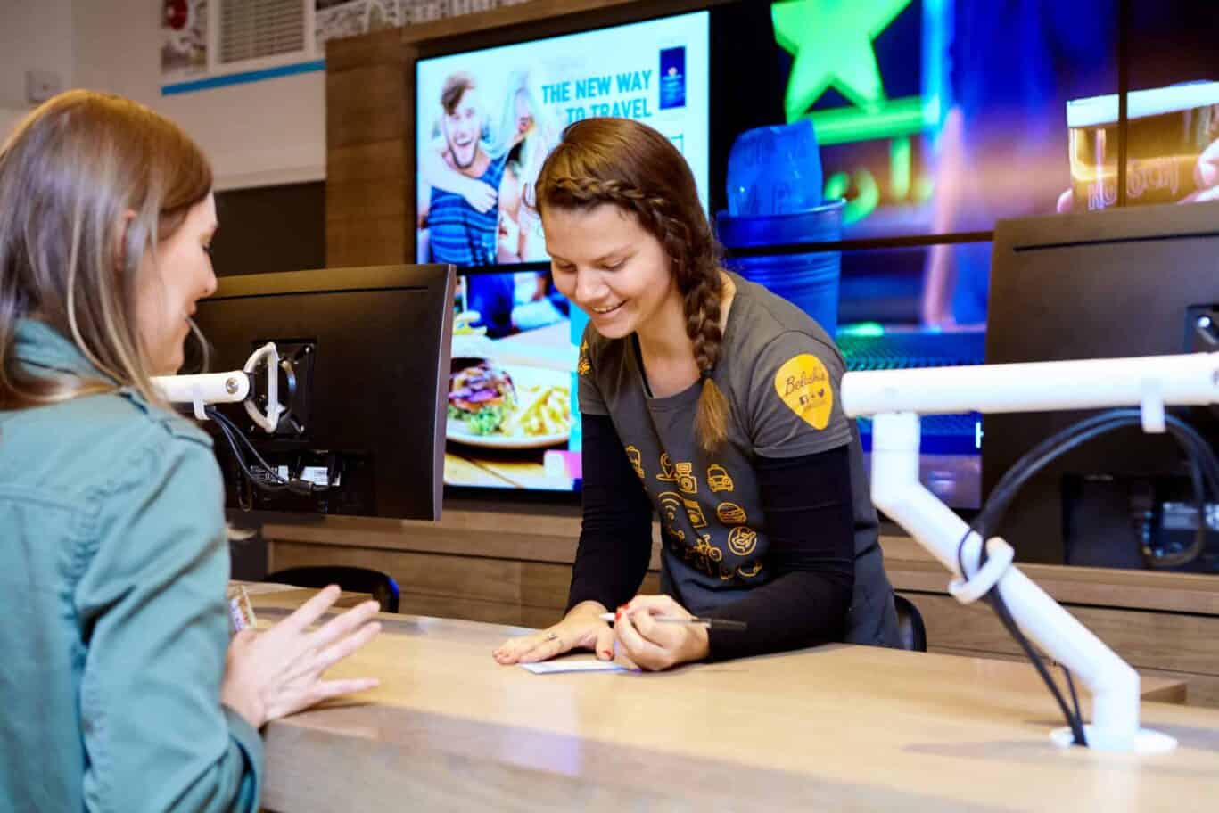 Friendly hostel staff assisting guest at London Bridge reception desk.
