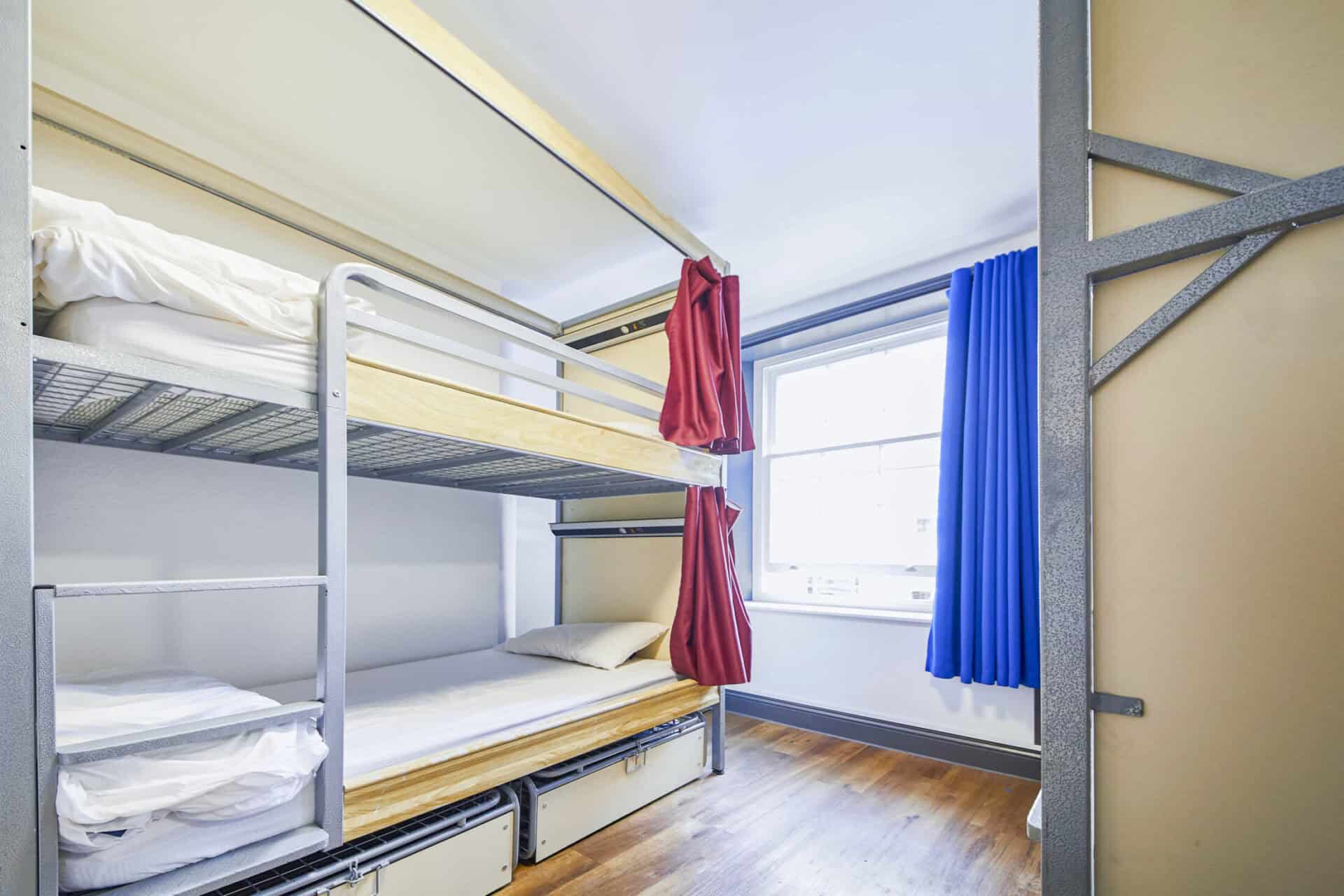 Dorm room at St Christopher's London Bridge with bunk beds and colourful curtains.