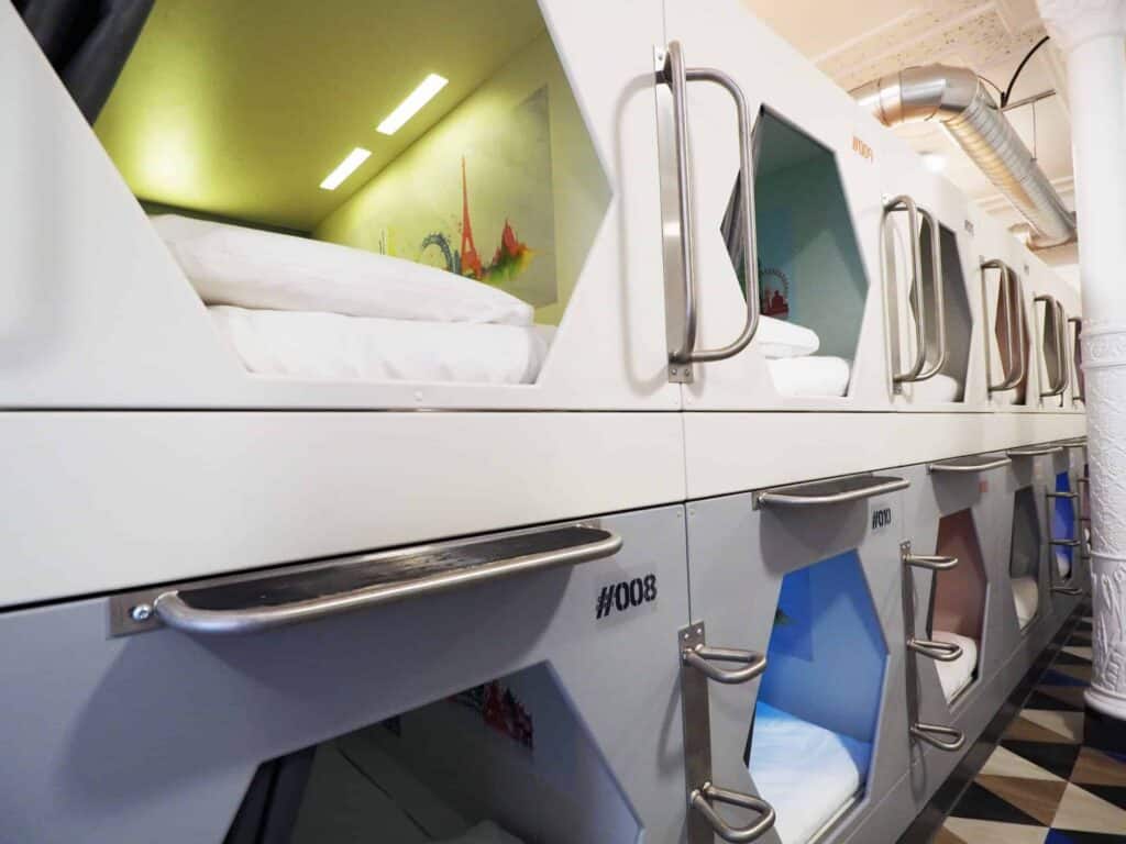 Capsule beds with individual sleeping pods in a contemporary hostel setting.