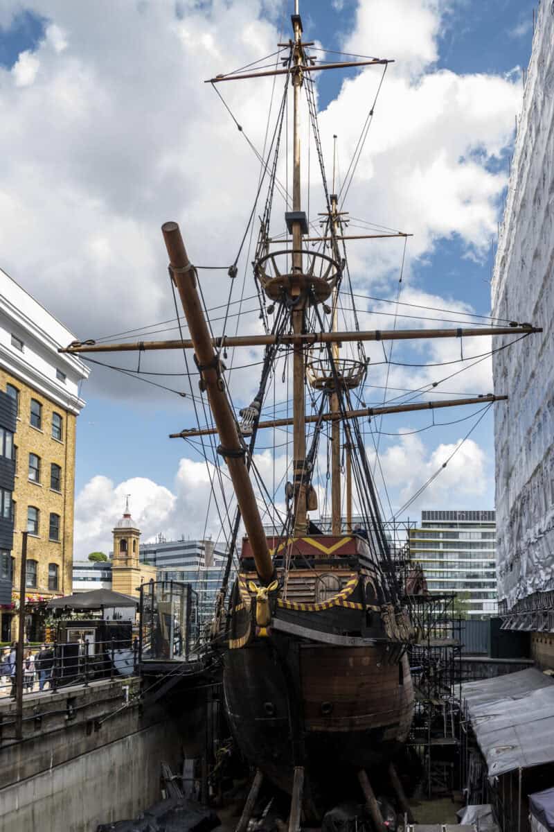 Hostel near London Bridge with historic ship and city skyline in the background.