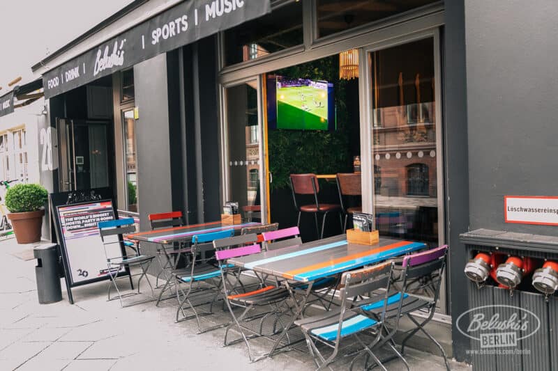 Outdoor seating area of Mitte Hostel in Berlin with colourful tables and chairs.