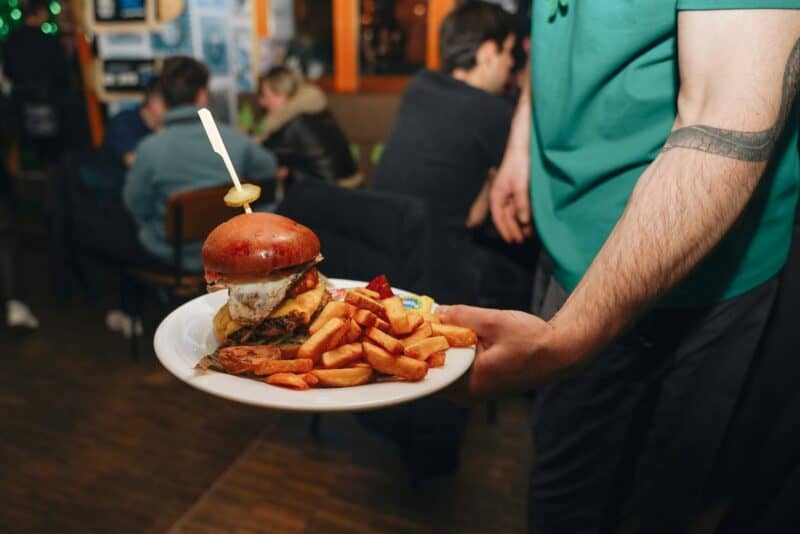 Delicious burger with fries on a plate, served at St Christopher’s Berlin - Mitte hostel.