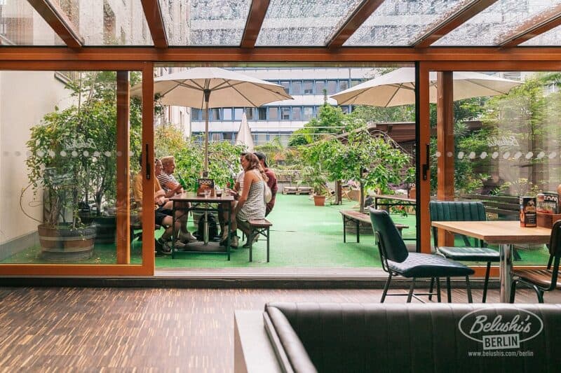 Outdoor garden at Mitte Hostel Berlin with seating and umbrellas.