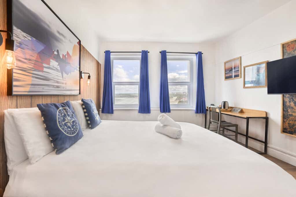 Hostel room at St Christopher’s Newquay featuring cozy beds, vibrant decor, and ocean views for a re.