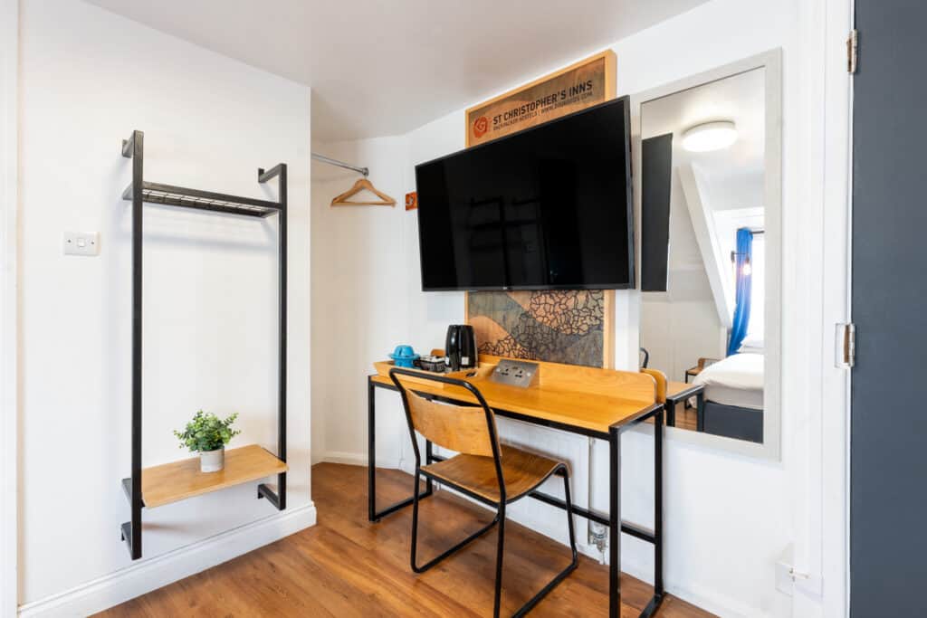 Modern hostel room with workspace and TV at St Christopher’s Newquay.