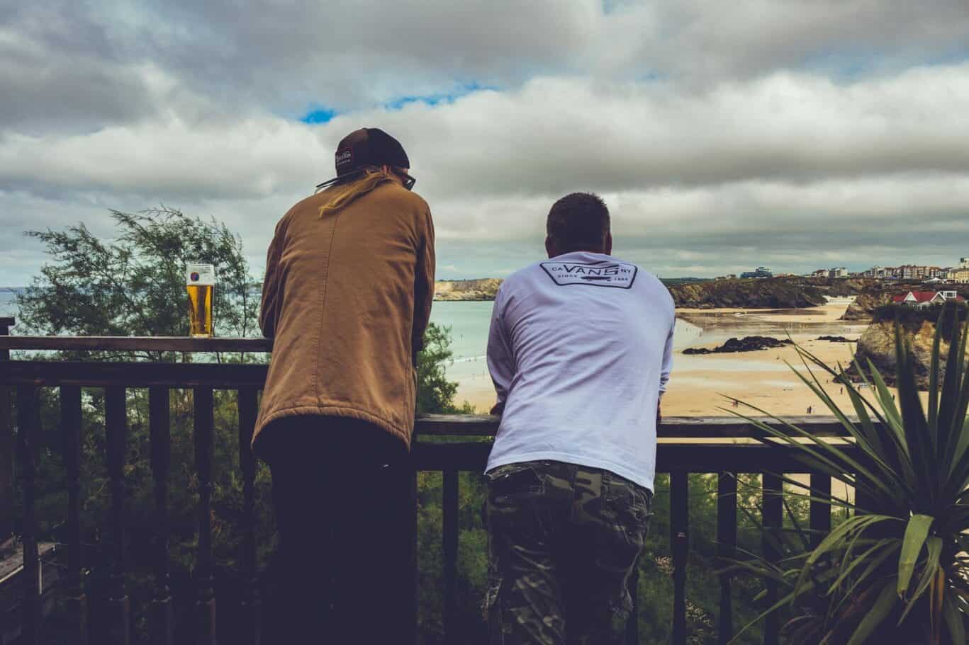 Two people overlooking the Newquay coastline from a balcony at St Christopher’s Hostel.