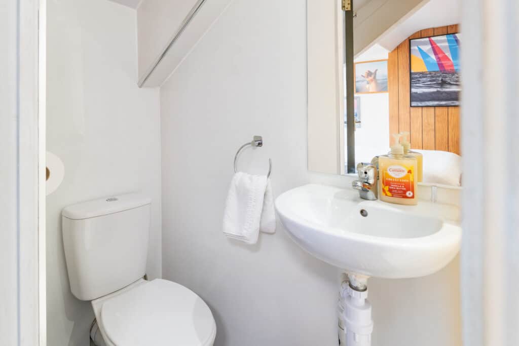Clean hostel bathroom with toilet and sink at St Christopher’s Newquay hostel. Perfect for traveller.
