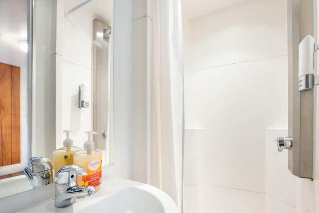 Modern bathroom with shower and toiletries at St Christopher’s Newquay hostel.