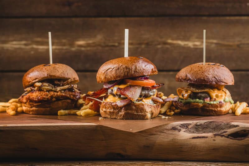 Delicious gourmet burgers with crispy fries served on a wooden board at St Christopher’s Edinburgh.