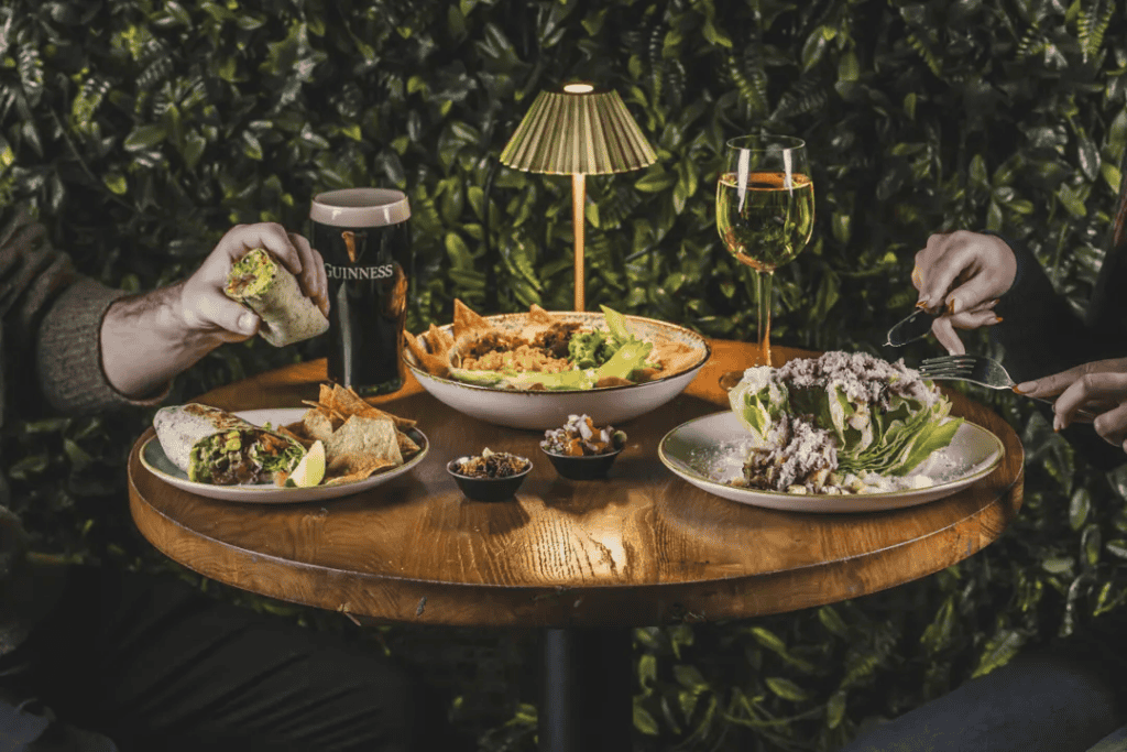 A cosy dining scene at St Christopher’s Edinburgh with drinks and food on a wooden table.