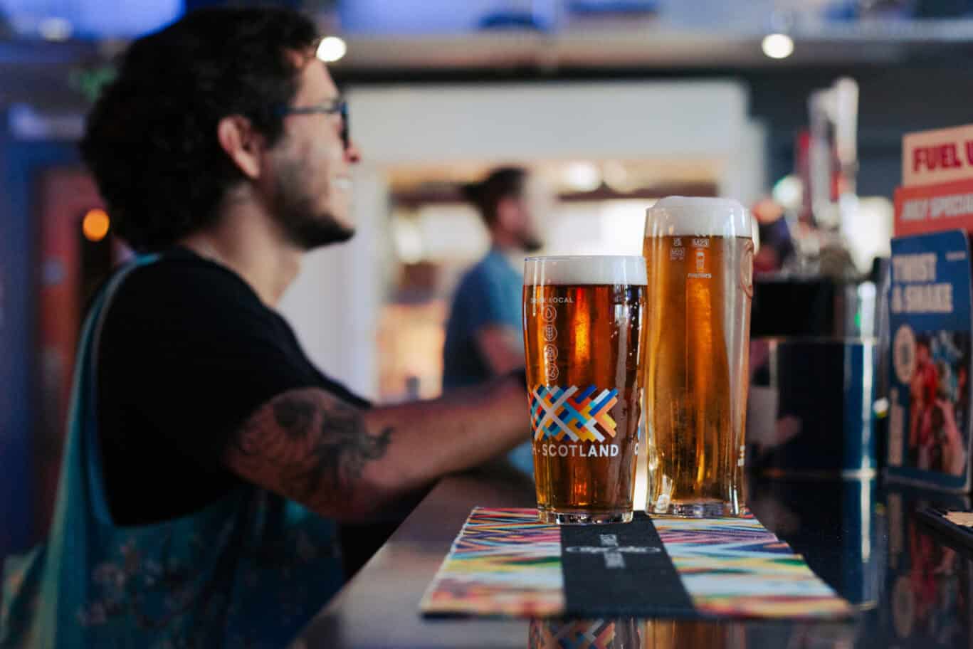 Person enjoying two pints of beer at a bar in Edinburgh, Scotland.