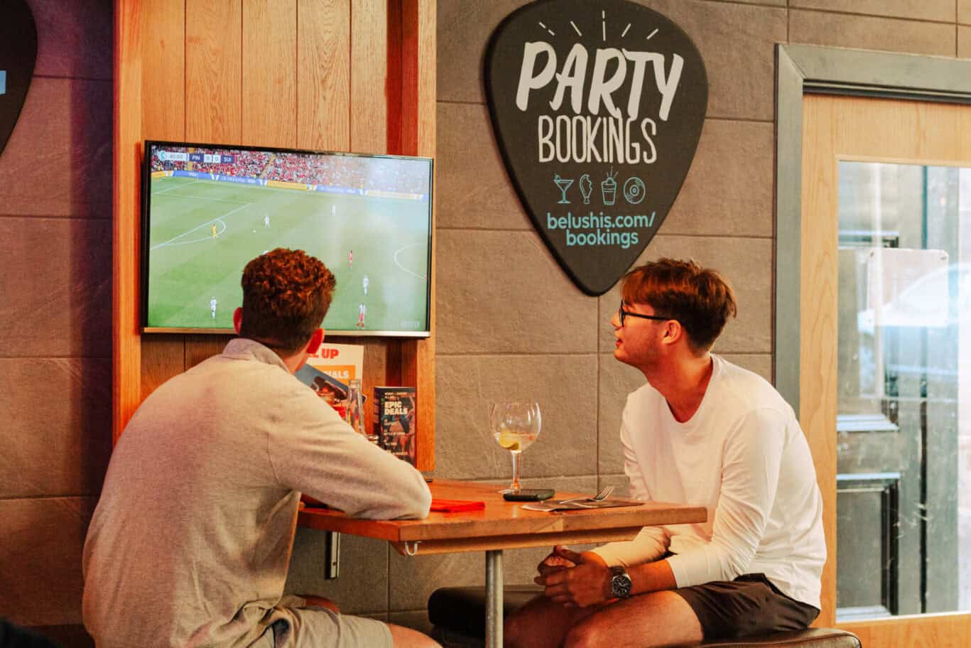 Two young men watching a football match on TV at a bar in Edinburgh.