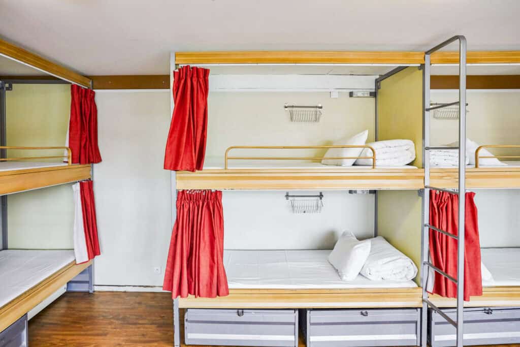 Dormitory bunk beds with red curtains at St Christopher’s Paris - Canal.