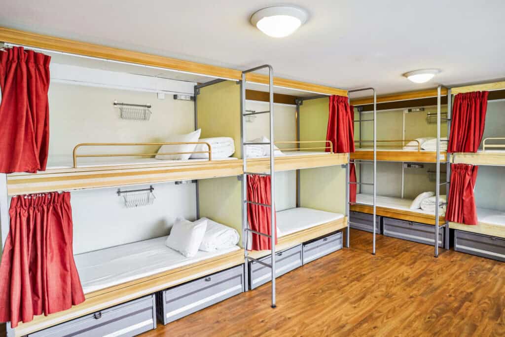 Bunk beds in a hostel dormitory at St Christopher’s Paris - Canal, featuring red curtains and wooden.
