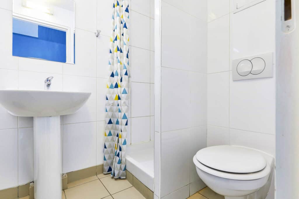 Clean and compact hostel bathroom with shower, toilet, and sink at St Christopher’s Paris - Canal.