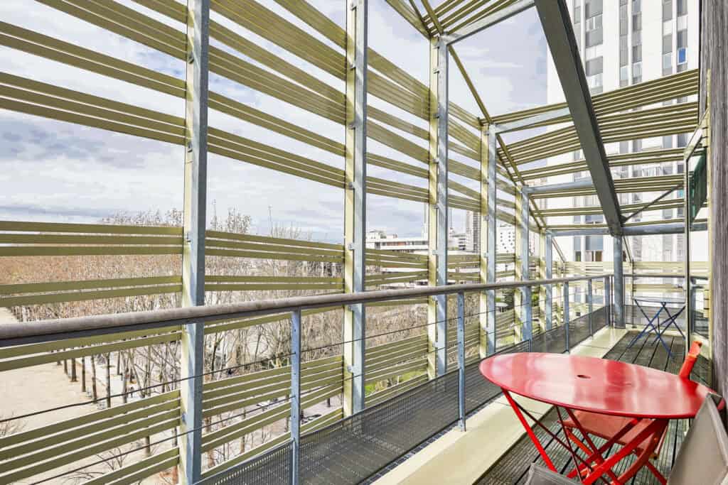 Balcony view at St Christopher’s Paris - Canal hostel with seating area and cityscape background.