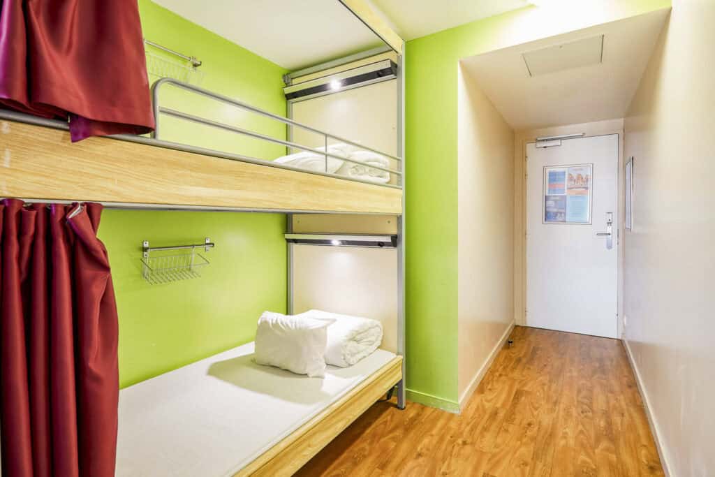 Bunk bed room at St Christopher’s Paris - Canal hostel with vibrant green walls and wooden floorin.