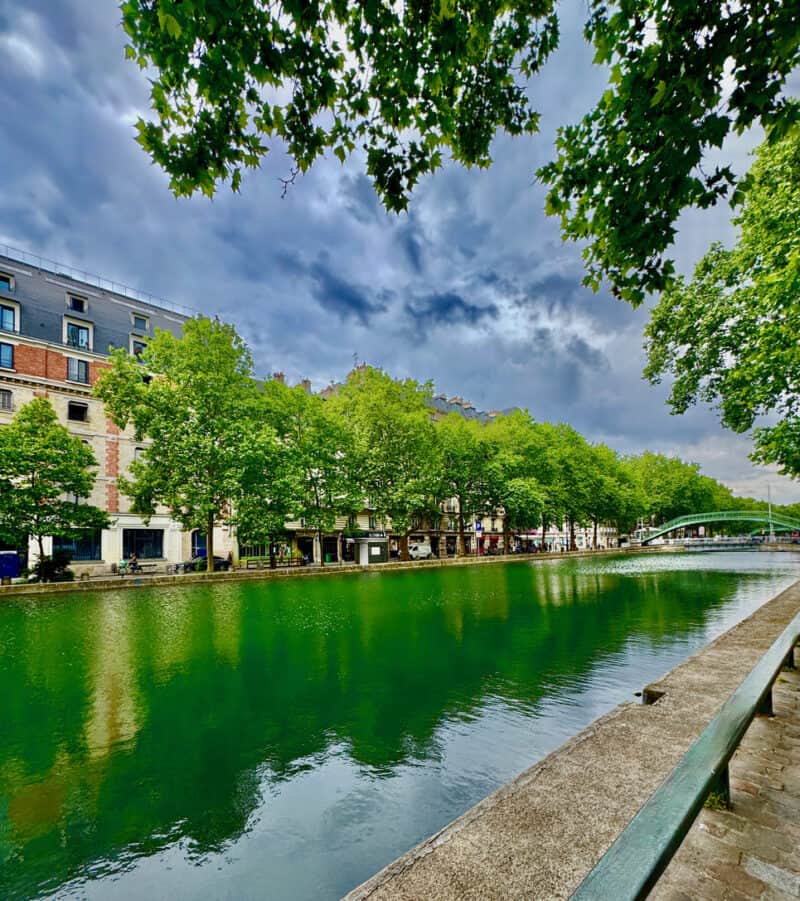 View of the canal near St Christopher's Paris - Canal, with trees and city buildings.