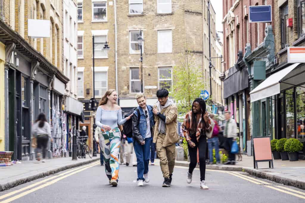 Group of young friends walking together on a city street in Shepherd's Bush, London.