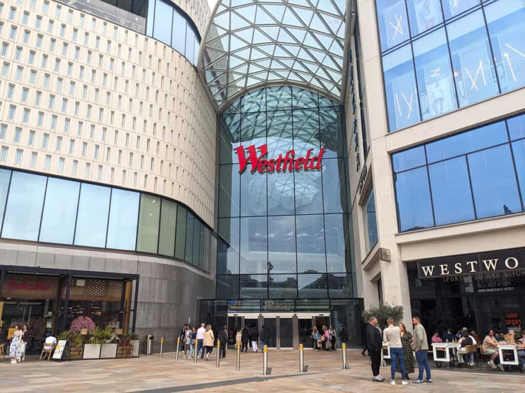 Westfield Shepherd's Bush shopping centre entrance with people walking and shopping.