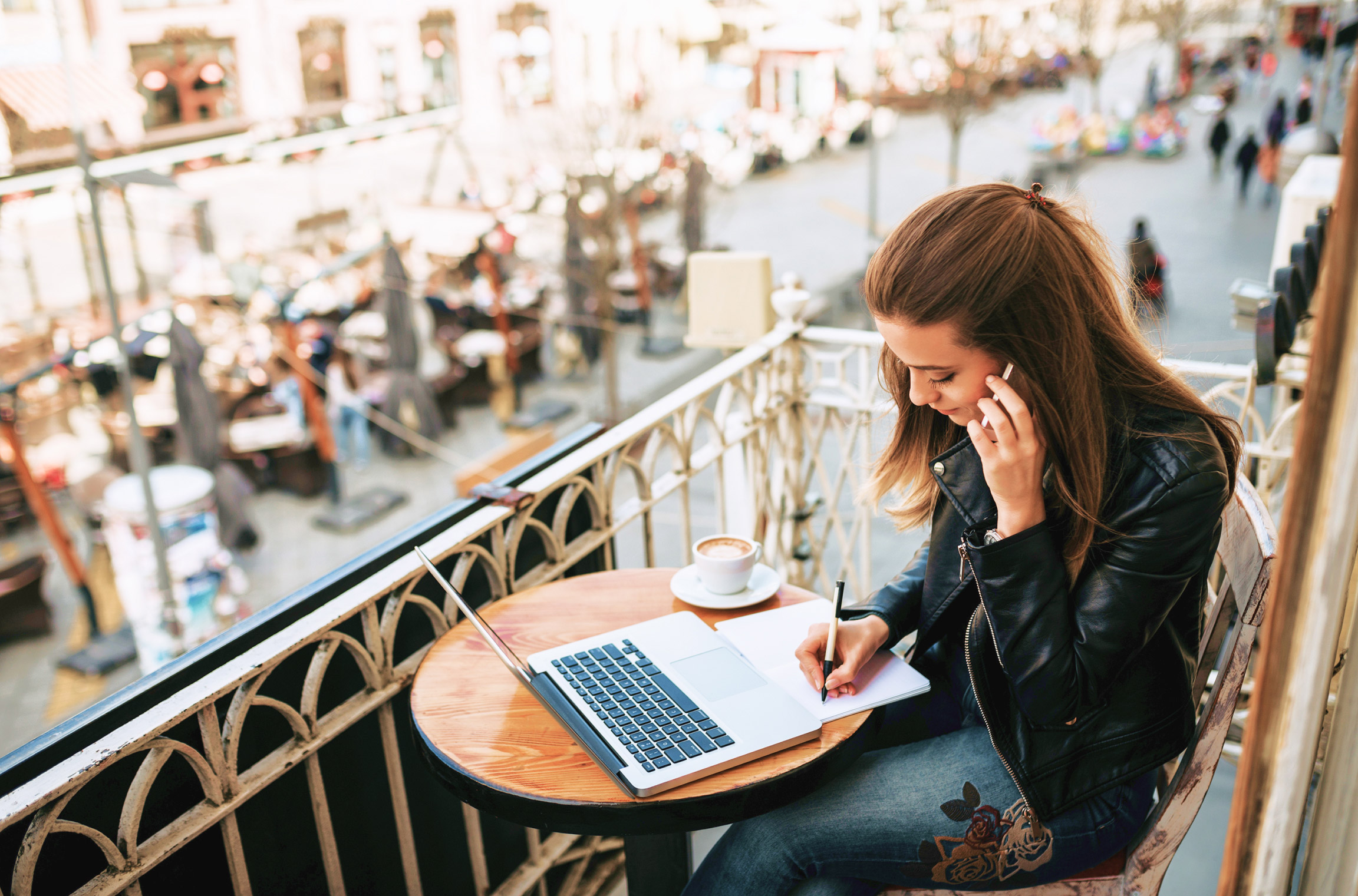 woman working on laptop from city balcony