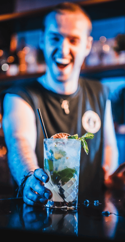 Vibrant bar scene with a smiling bartender serving a refreshing cocktail at St Christopher’s Vienna.