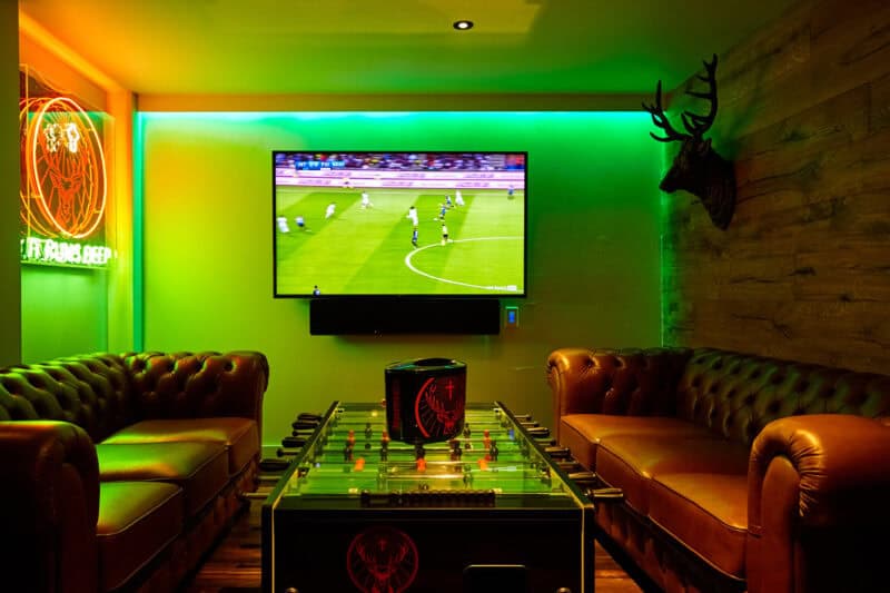 Cozy lounge with football game on TV and foosball table.