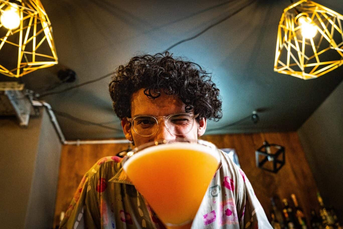 Young man enjoying a cocktail at St Christopher's bar with stylish lighting.